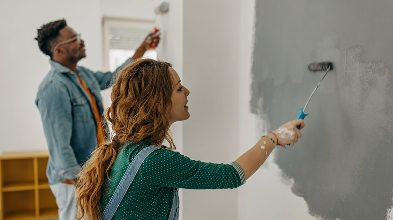 Man and woman painting an interior wall a dark gray