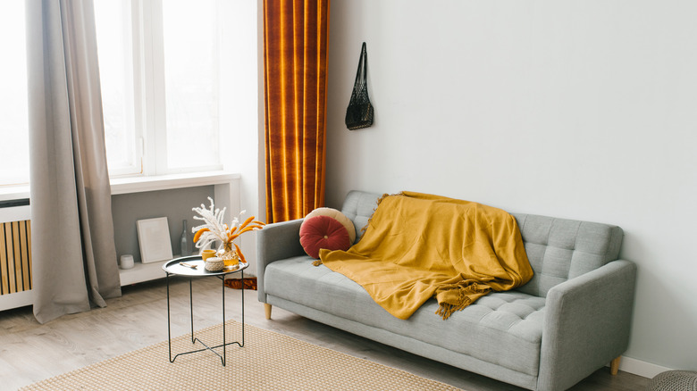 Gray-walled living room with gray furniture and orange curtains and accessories