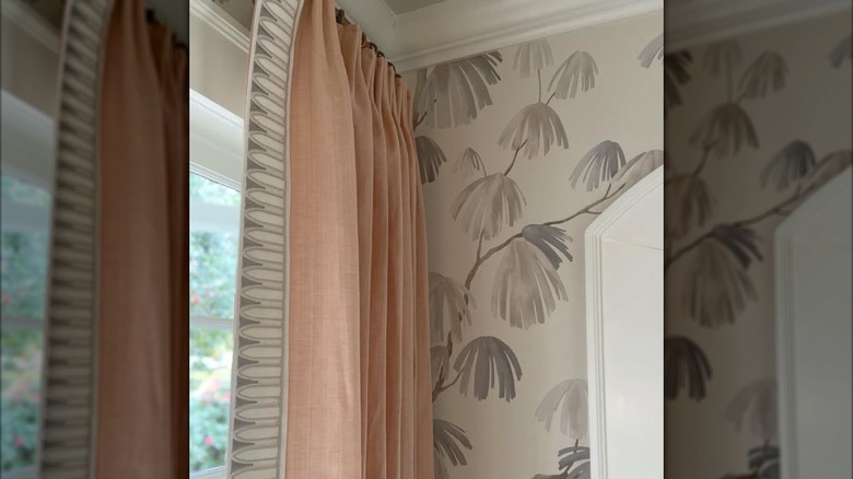 Warm blush pink window curtains against gray patterned wallpaper