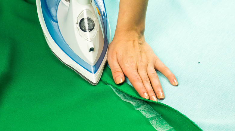 person hemming curtain with hem tape