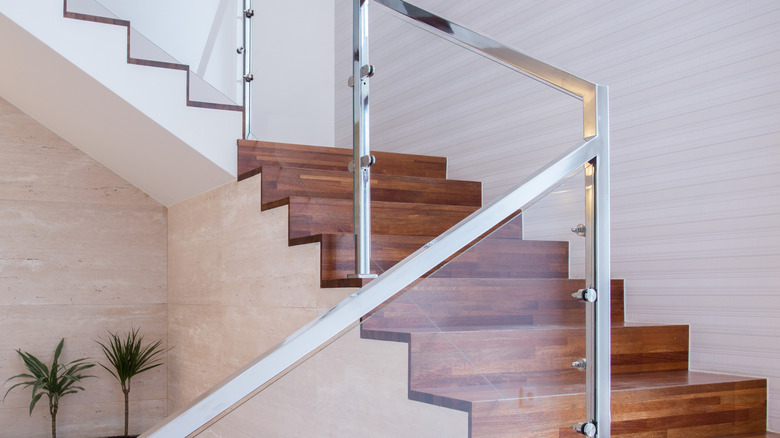 Stylish wooden staircase with glass banister and railing in modern home