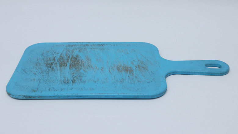 A scratched and stained blue plastic cutting board
