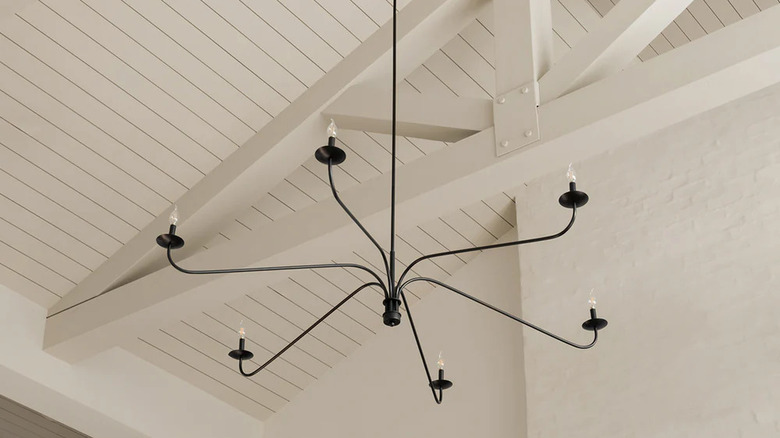 black metal chandelier hanging from shiplap ceiling