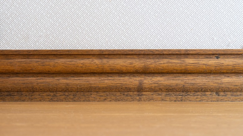 Dark wood baseboard with light wall and floor