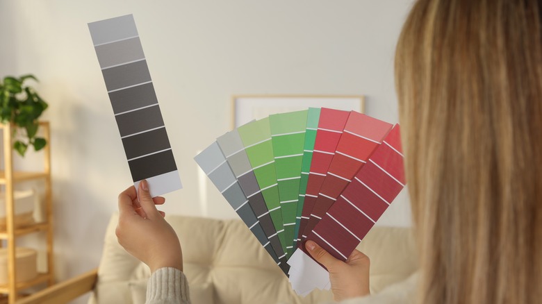 Woman holding color swatches up in living room