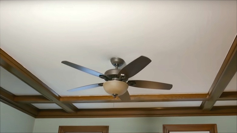 Dark wood coffered ceiling with ceiling fan in the middle