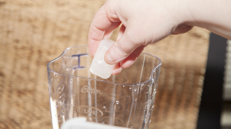 Hand dropping ice in a blender