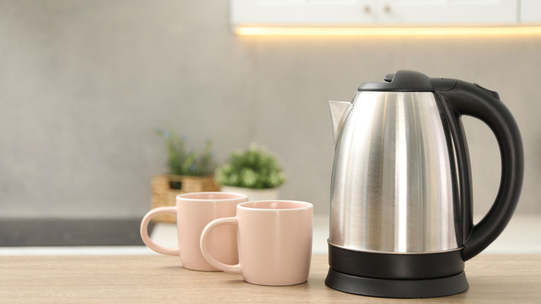 Electric kettle next to two coffee cups on a kitchen table