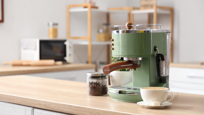 Modern espresso machine with coffee beans and a mug on a wooden table in a kitchen