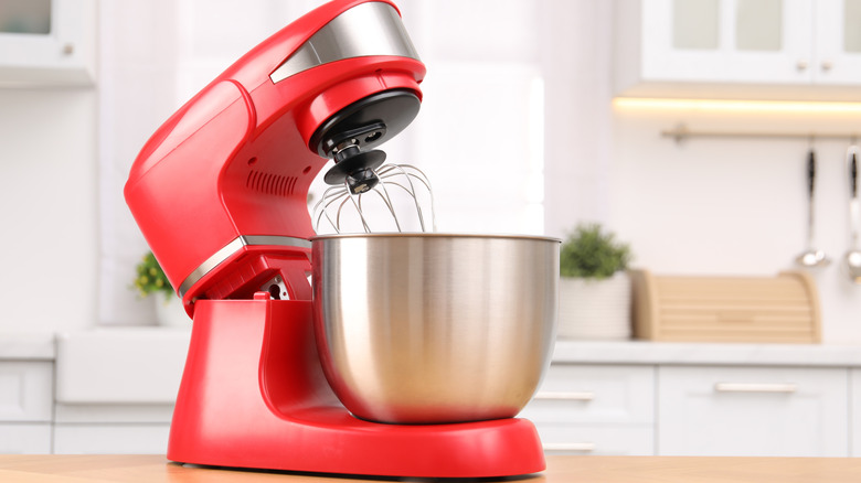 Red stand mixer on a wooden table in a kitchen