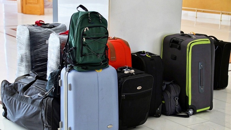 pile of backpacks, suitcase, and wrapped luggage on white tile