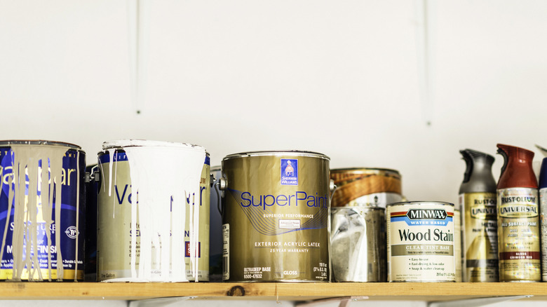 Paint cans and wood stains on a wooden shelf