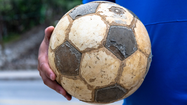 Hand holding dirty soccer ball