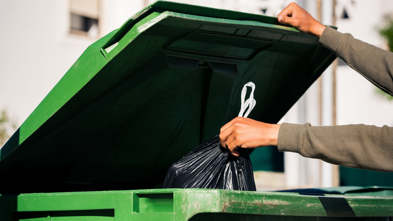 placing trash bag in bin