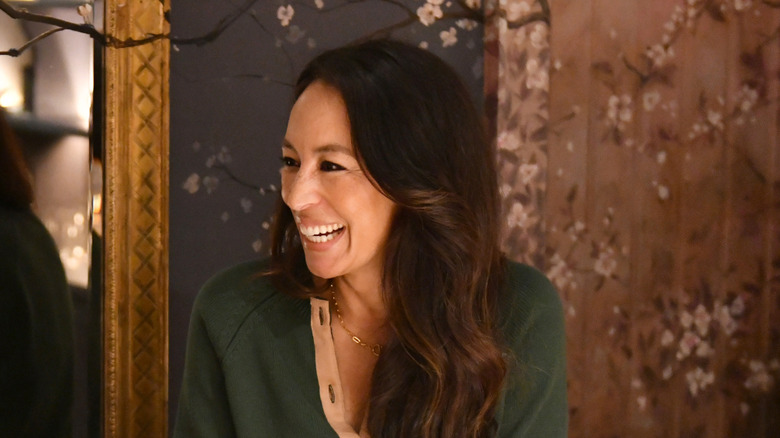 Joanna Gaines smiles while wearing a green sweater