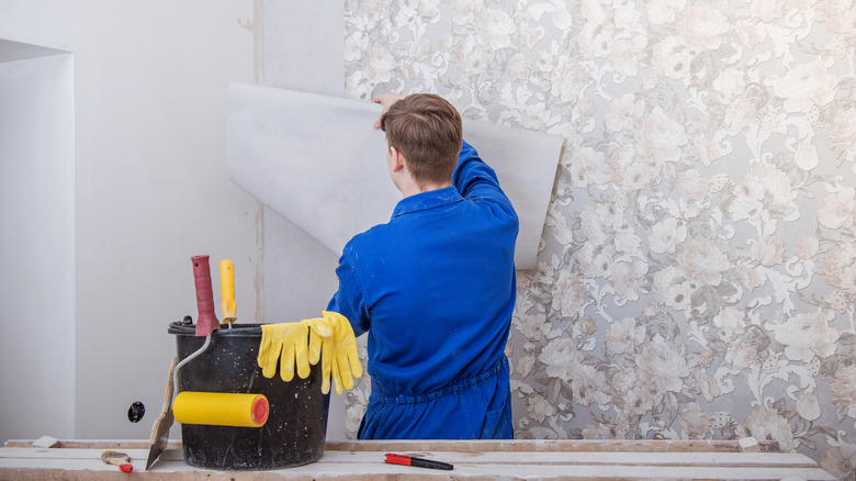 man installing floral wallpaper