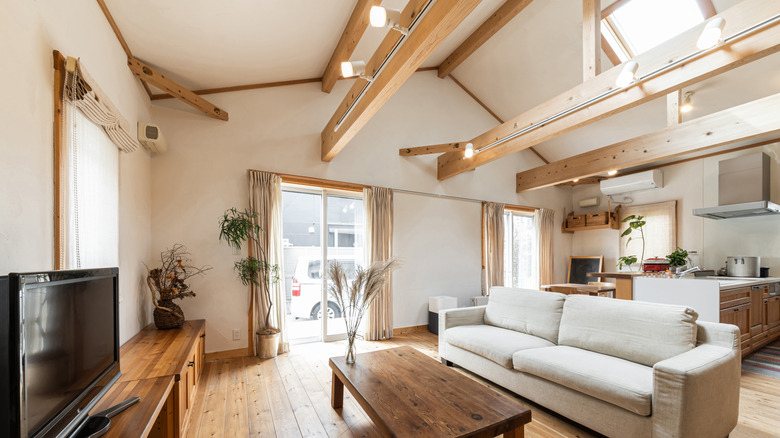 Open-concept living room and kitchen with lights on ceiling beams