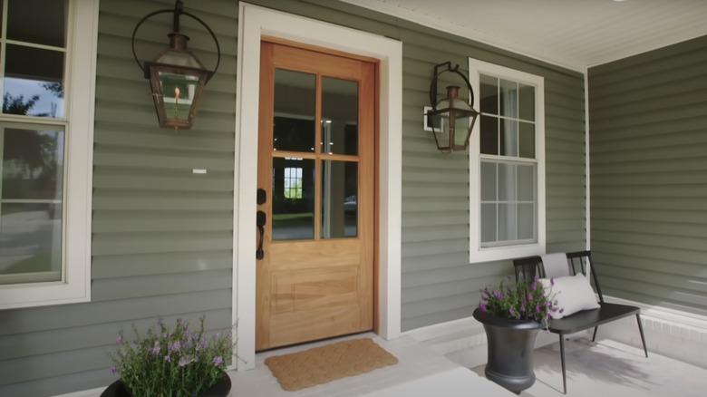 Two gas lanterns flank a wooden front door