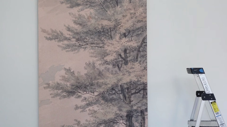 Panel of wallpaper against a white wall with a ladder next to it
