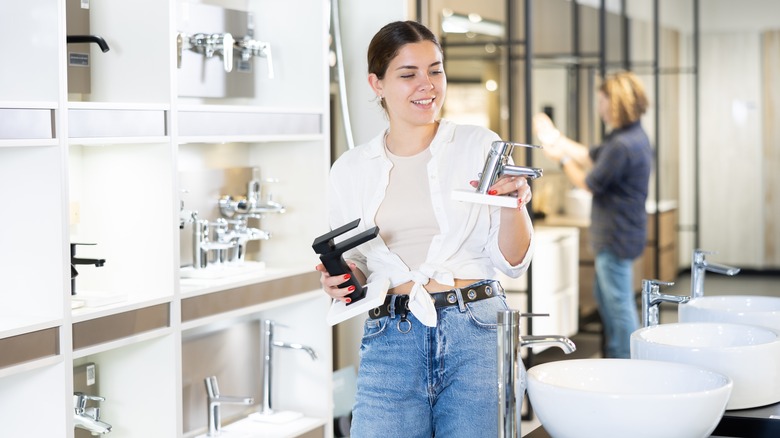 Woman holding faucets in two different types of metals