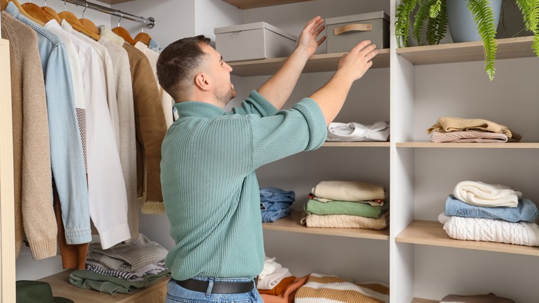 man reaching for box in a walk-in closet