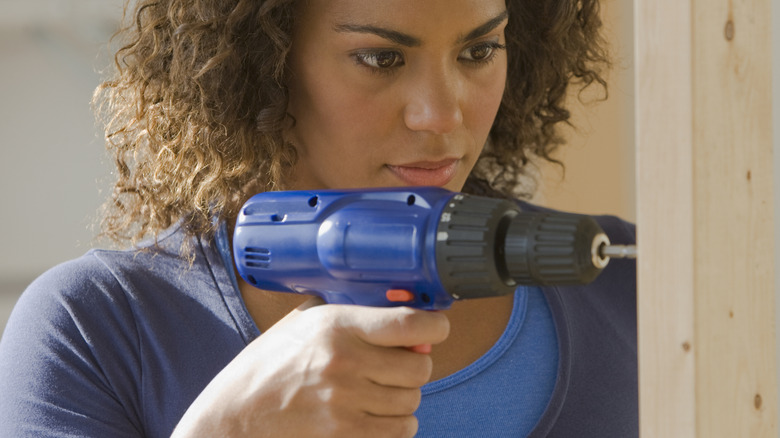 Woman drilling a hole using a cordless drill