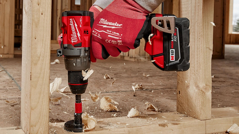 A Milwaukee cordless drill boring holes in wall studs