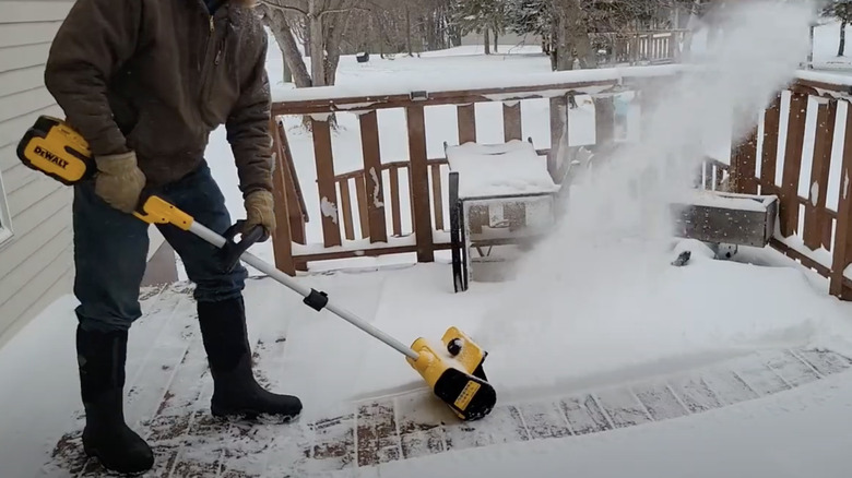 Man using DeWalt snow shovel on snowy deck