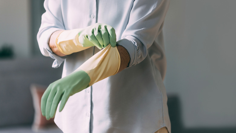 Person pulling on green rubber gloves