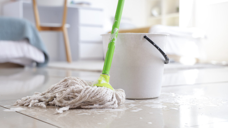 Mop and bucket on soapy tile floor