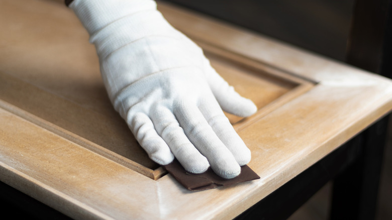 person sanding veneer cabinet