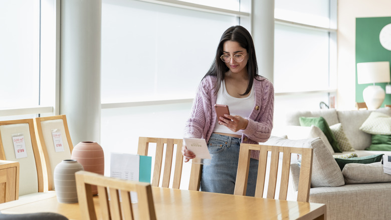 Woman looking at wooden dining room table in furniture store