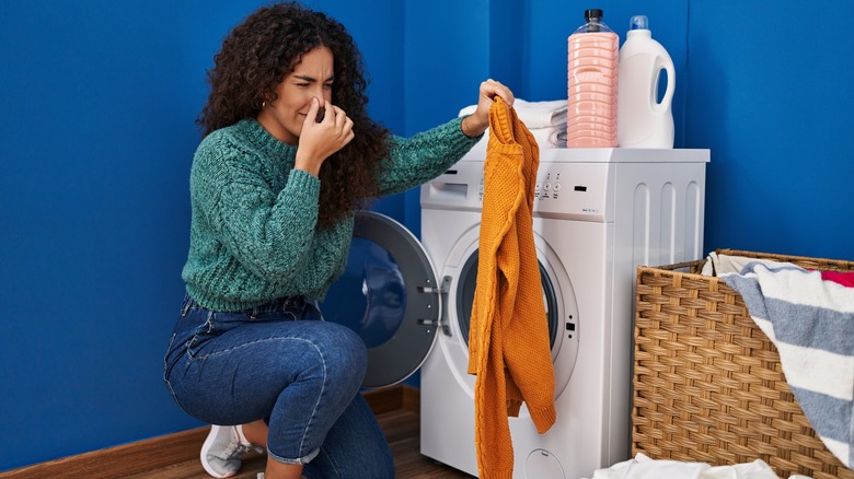 person doing laundry holding nose