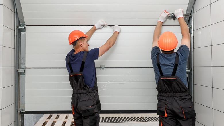 Workers installing a new sectional garage door