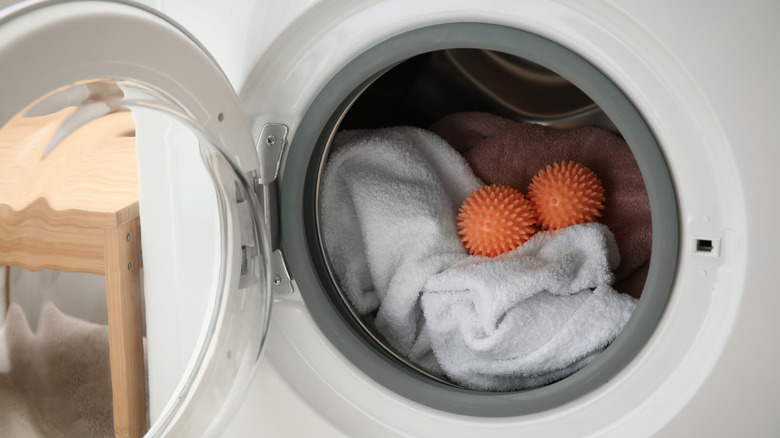 Two orange plastic dryer balls in an open dryer with white towels