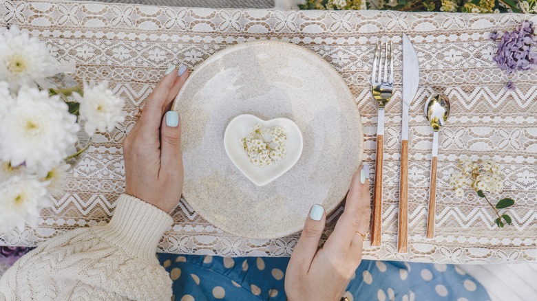 Woman sets table with cream-colored dishware