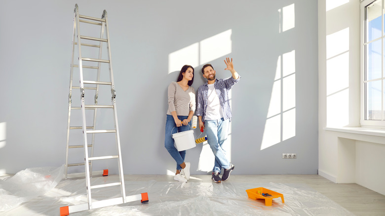 A couple standing next to a ladder in a room being renovated