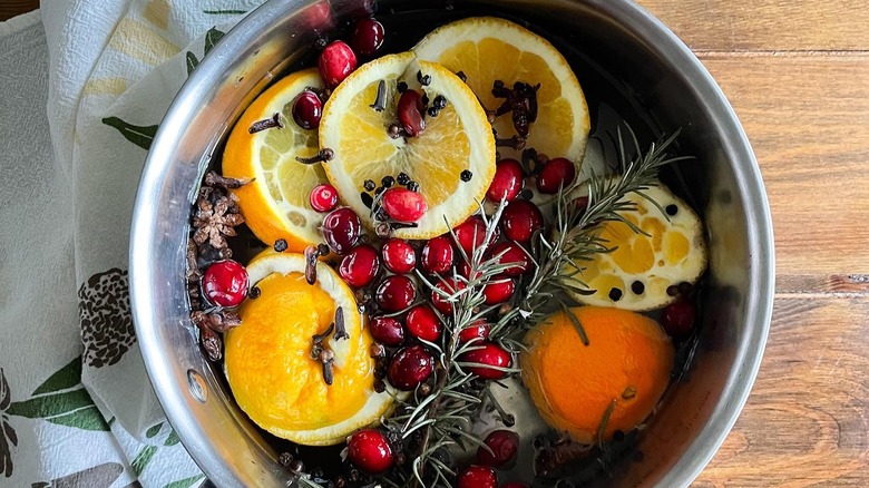 Holiday simmer pot with cranberries, star anise, cinnamon sticks, orange slices, and dried herbs