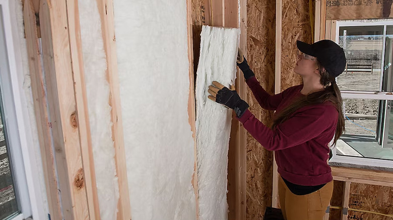 woman hanging fiberglass insulation panel