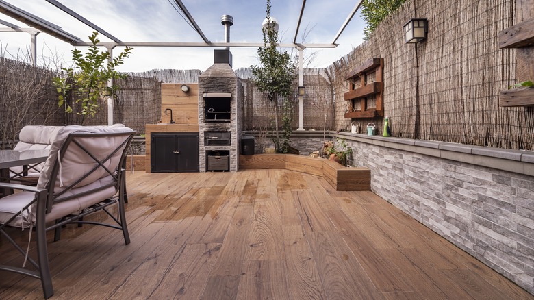 An outdoor space has matte wooden flooring with water spills in the middle