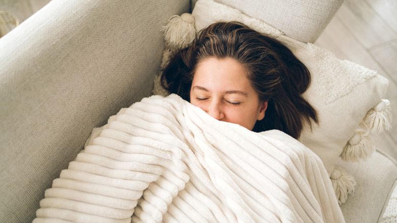 Woman wrapped in a white blanket with eyes closed