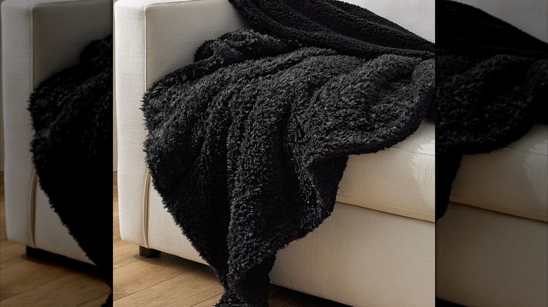 Black faux fur blanket draped on a couch