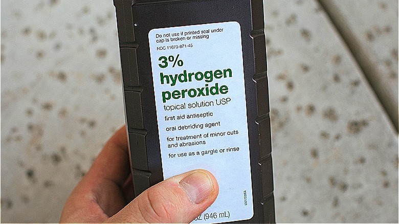 Person holding hydrogen peroxide bottle