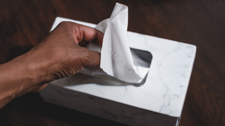 Hand pulling tissue from box