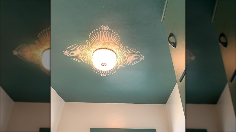 Teal ceiling with white painted stencil design around the light fixture