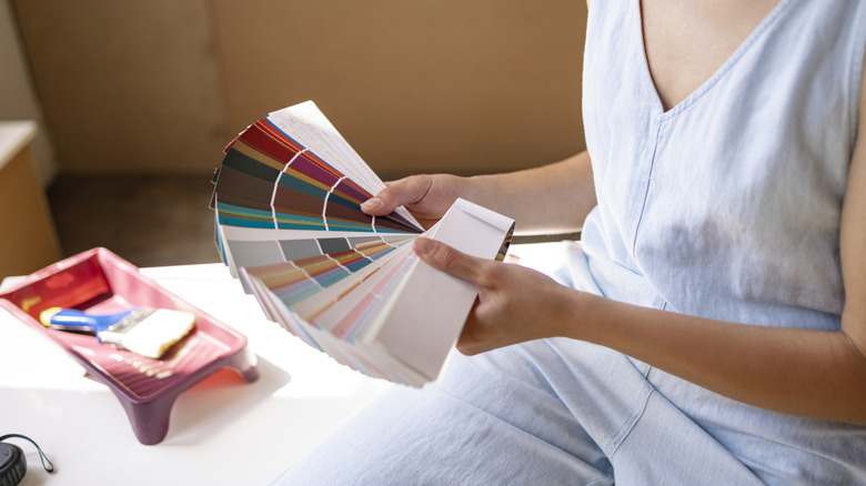 Person looking at paint samples with a brush and tray beside her