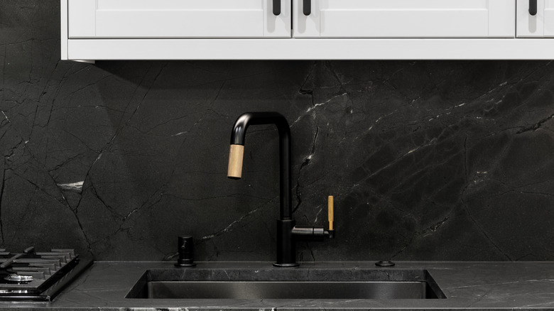 A black backsplash behind the sink in a kitchen