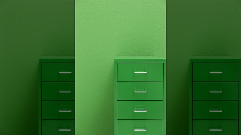 A green metal locker rests against a green wall