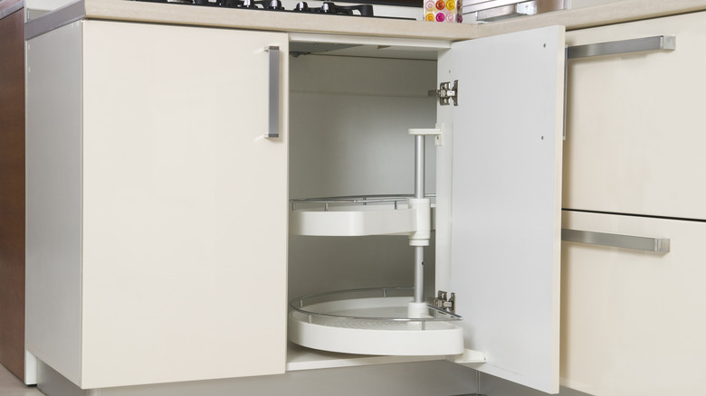 Empty lazy Susan shelves inside an open white kitchen cabinet