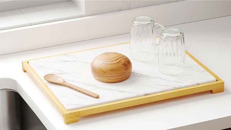 Marble-looking white diatomaceous earth dish drying mat with dishes on top next to sink